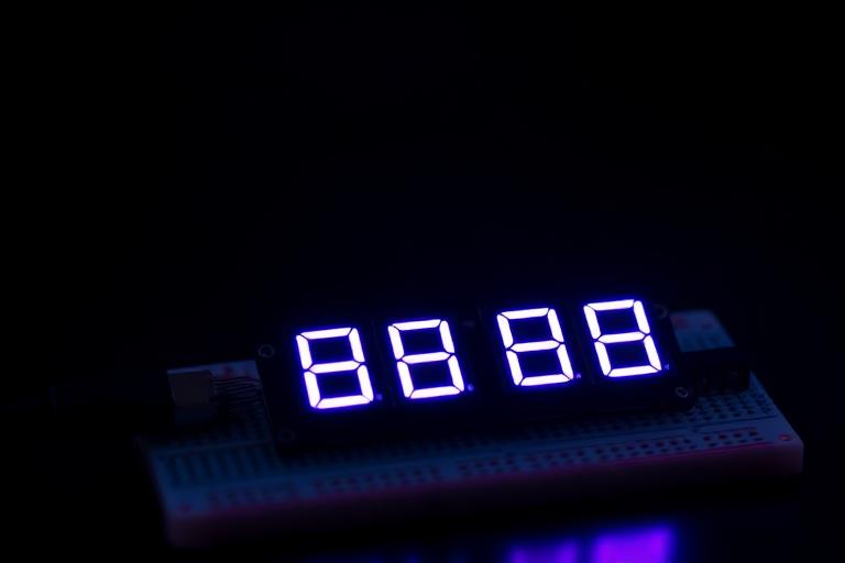 Seven-segment LED display glowing on a breadboard next to a pushbutton